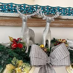 two silver deer figurines sitting on top of a mantle