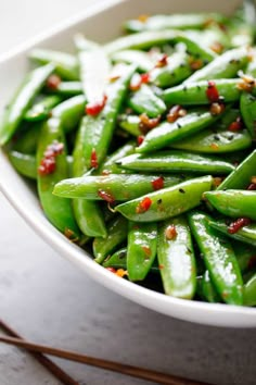 a white bowl filled with green beans covered in seasoning