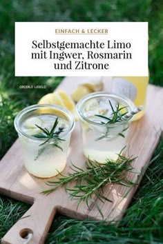 two glasses filled with lemonade sitting on top of a cutting board in the grass