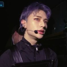 a man with purple hair wearing a headset