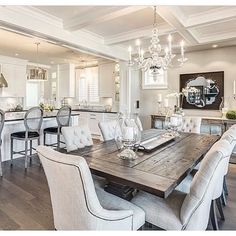 the dining room table is surrounded by white chairs and chandeliers in this kitchen