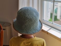 a young boy wearing a crocheted hat looking out the window