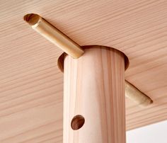 a close up of a wooden structure with holes in the wood and two pegs attached to it