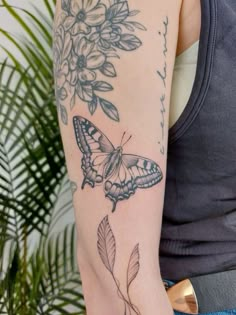 a woman's arm with a butterfly and flower tattoo on the left side of her arm