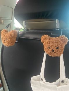 two teddy bears hanging from the back of a car seat