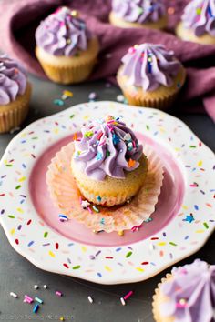 cupcakes with purple frosting and sprinkles on a plate