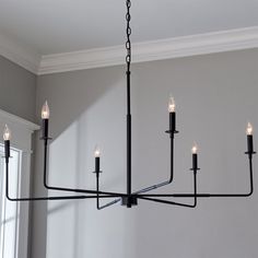 a black chandelier with five candles hanging from it's center and four arms