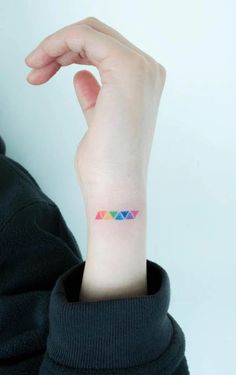 a woman's arm with a small colorful triangle tattoo on her left wrist,