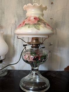 a lamp that is sitting on top of a table next to a vase with flowers in it