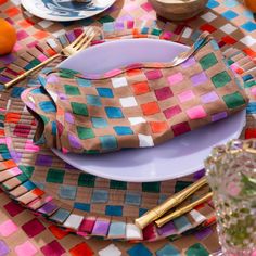 the table is set with colorful plates and napkins