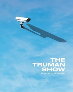 the truman show poster with a security camera flying in the air and blue sky behind it