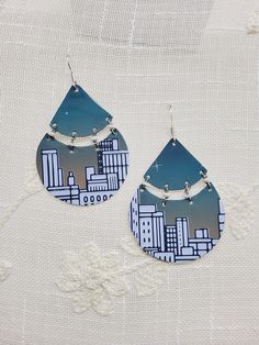 the earrings are designed with cityscape and blue tint, on white fabric