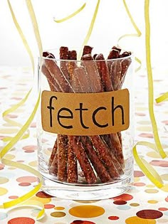 a glass filled with brown dog treats on top of a polka dot table cloth next to yellow streamers