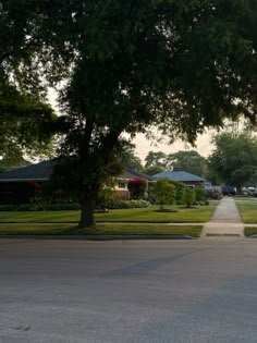 an empty street with houses and trees in the background