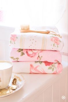 three towels stacked on top of each other next to a cup and saucer