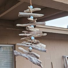 a wind chime made out of driftwood and blue balls hanging from the ceiling