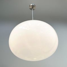 a white light hanging from a ceiling fixture in a room with gray walls and flooring