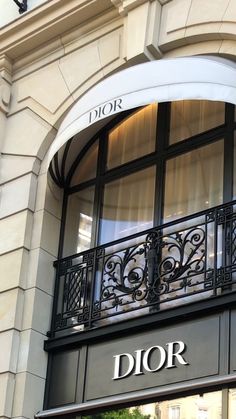 a store front with the name dior on it's glass window and wrought iron balconies