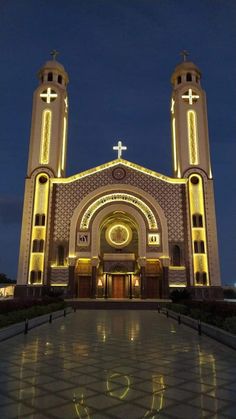 a large church with two towers and lights on it's front entrance at night