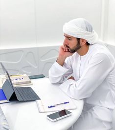 a man with a turban sitting at a desk in front of a laptop