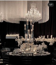 an elegant wedding reception with chandeliers and white flowers on the centerpieces