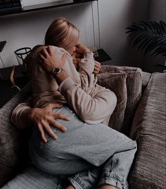 a woman sitting on top of a couch hugging another person's back in a living room