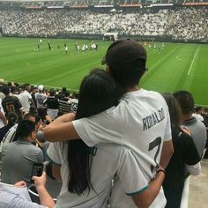 two people hugging each other in front of a crowd at a soccer game on a field