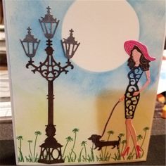 a woman is walking her dog in front of a lamp post with the moon behind it