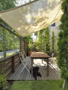 a black dog sitting on top of a wooden deck next to a table and chairs