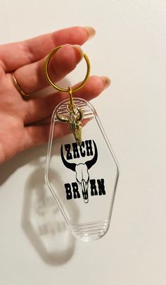 a hand holding a glass keychain with a bull's head on it