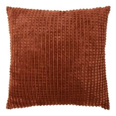 an orange velvet pillow with pleated lines on the front and back, sitting on a white background