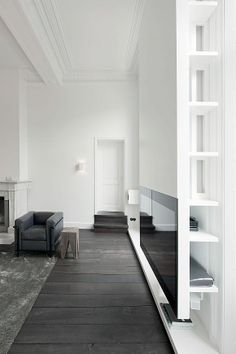 an empty living room with white walls and black furniture in the center, along with a fireplace