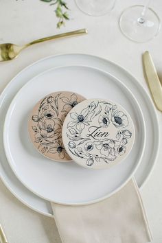 two decorated cookies sitting on top of a white plate next to gold forks and silverware