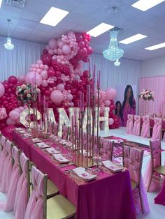 a table with pink and white balloons on the wall in front of it is set up for a party