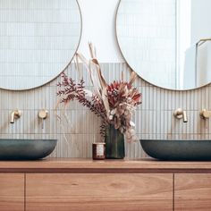 two round mirrors are on the wall in this bathroom with wood countertops and double sinks