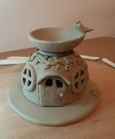 a ceramic birdhouse on a wooden table