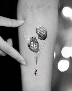 a heart shaped balloon with a human brain attached to it's side tattoo on the left inner arm