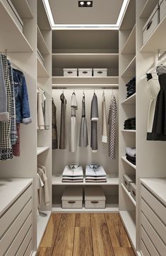 an organized walk - in closet with white drawers and clothes hanging on the shelves,