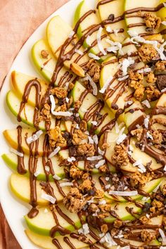 an apple salad with nuts and chocolate drizzled over it on a white plate