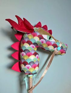 a colorful sea horse head hanging on the wall with a ribbon around it's neck