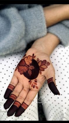 a woman's hand with hennap and flowers painted on the top of it