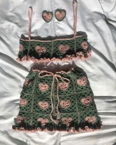 two pieces of crocheted clothing laying on top of a bed