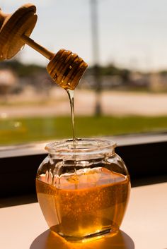 honey being poured into a glass jar