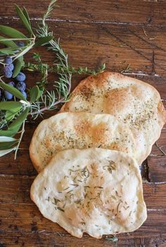 two pieces of bread sitting on top of a wooden table next to blueberries and green leaves