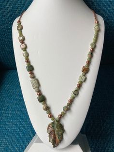 An asymmetrical, natural green Jade necklace, Jasper leaf carved pendant, square green Rhyolite beads and accented with copper beads vintage chain necklace necklace is 30 inches in length and can be made SHORTER! Genuine green Jade 6mm Jasper leaf pendant 1 3/4 X 1 1/4'' Green Rhyolite beads 10 X 10 X 3mm  and ovals 15 X 10 X 3mm and 8 & 10mm faceted rounds All my necklaces are different and would be considered one of a kind. I've been selling on eBay since 2003 Came to Etsy to sell jewelry. Returns and exchange details ► RETURNS / EXCHANGES All items are handcrafted and custom pieces therefore we don't usually accept returns or exchanges on jewelry unless the fault was ours. Screens do not always reflect the same colors as well as seeing them in person. However, I understand that these pi Luxury Jasper Elegant Necklaces, Pearl And Jasper Necklace, Nature-inspired Jade Pendant Necklace, Green Jasper Spiritual Jewelry, Green Beaded Rectangular Necklace, Nature-inspired Green Jade Necklaces, Handmade Green Rectangular Necklace, Green Rectangular Beaded Necklace, Green Rectangular Gemstone Beads Jewelry