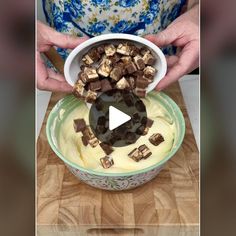 a bowl filled with chocolate and marshmallows on top of a wooden cutting board