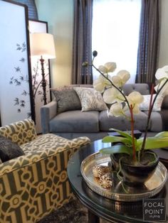 a living room filled with furniture and flowers on top of a glass topped coffee table