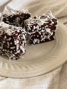 three pieces of chocolate cake on a plate with coconut flakes and shredded white sugar