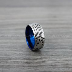 a blue and silver ring with an egyptian pattern on it, sitting on a wooden surface