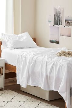 a bed with white sheets and pillows in a room